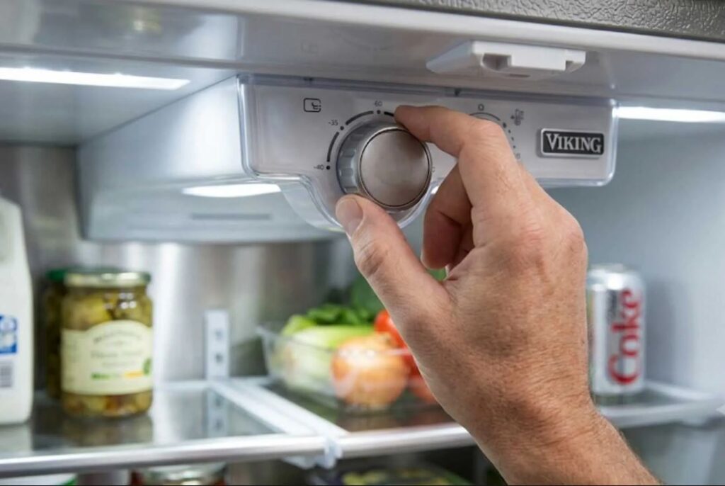 Hand adjusting the temperature control dial inside a Viking refrigerator