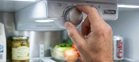 Hand adjusting the temperature control dial inside a Viking refrigerator